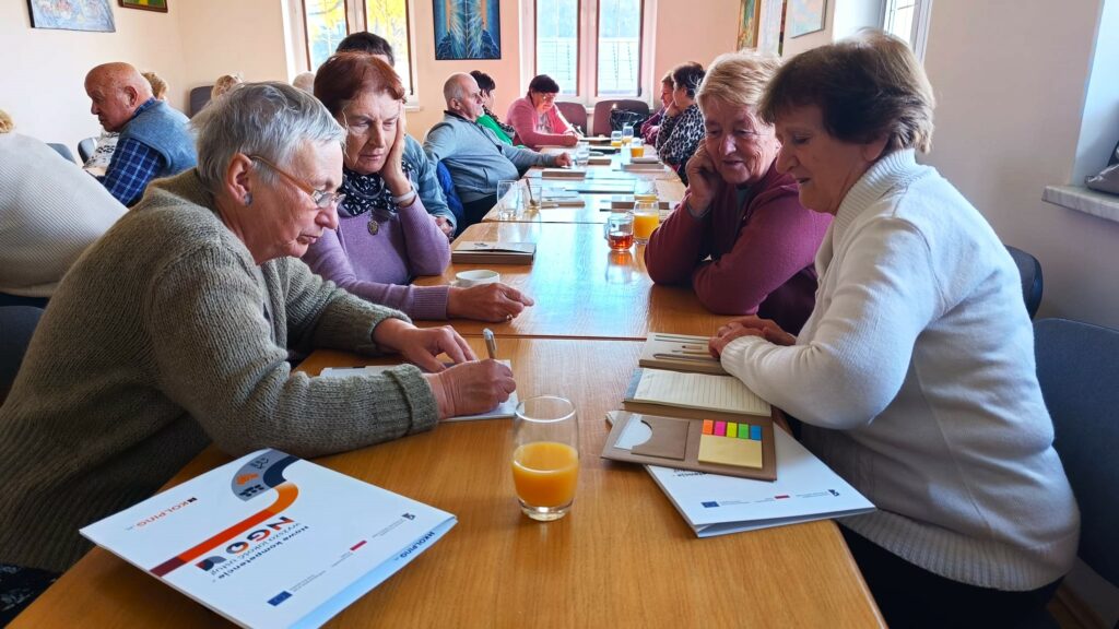 zdjecie przedstawia osoby siedzace przy stole sali szkoleniowej i uczestniczące w szkoleniu