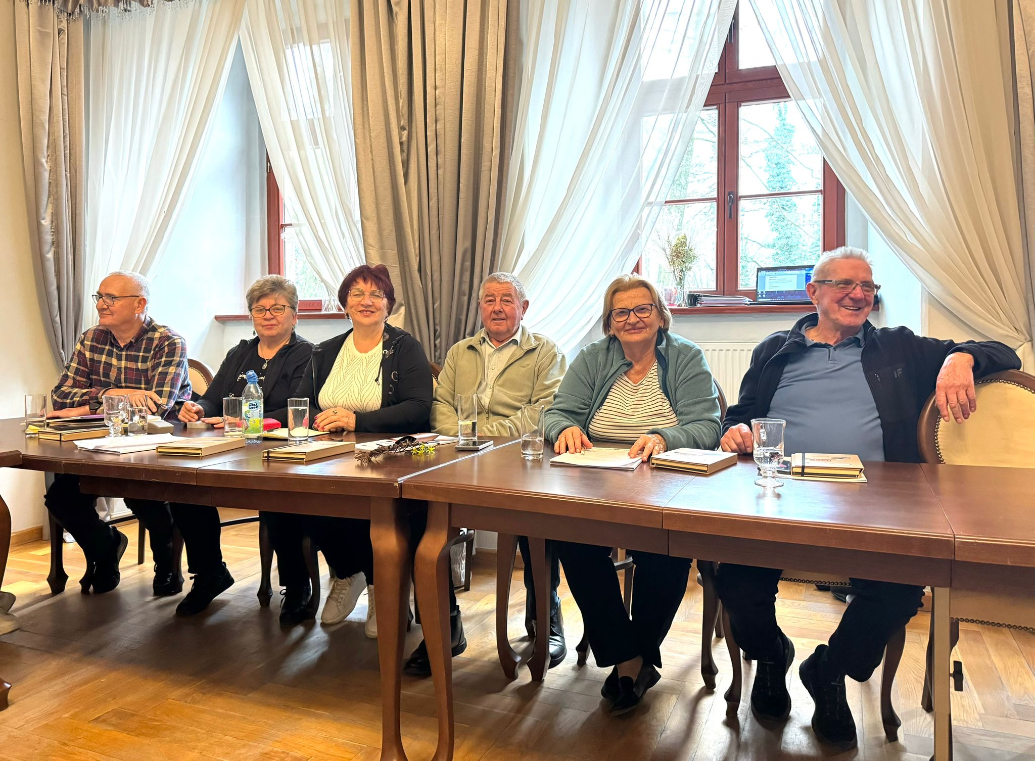 grupa uczestników szkolenia siedzi przy stołach i pozuje do zdjęcia