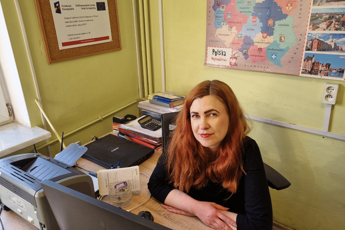 zdjęcie przedstawia kobietę siedzącą w biurze, przy biurku przed komputerem.