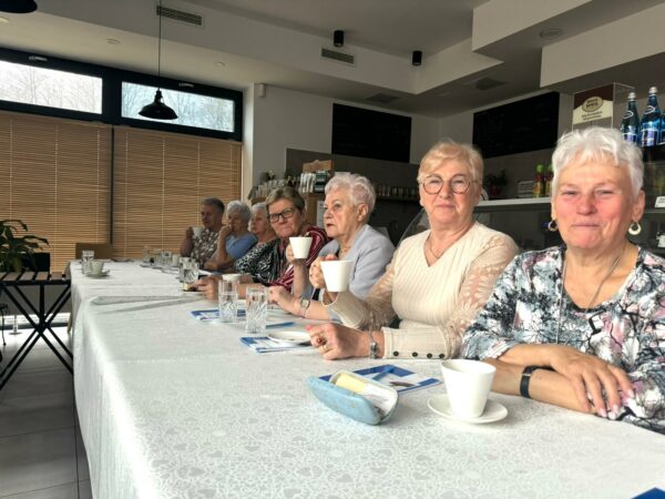 grupa uczestniczek szkolenia siedzi przy stołach