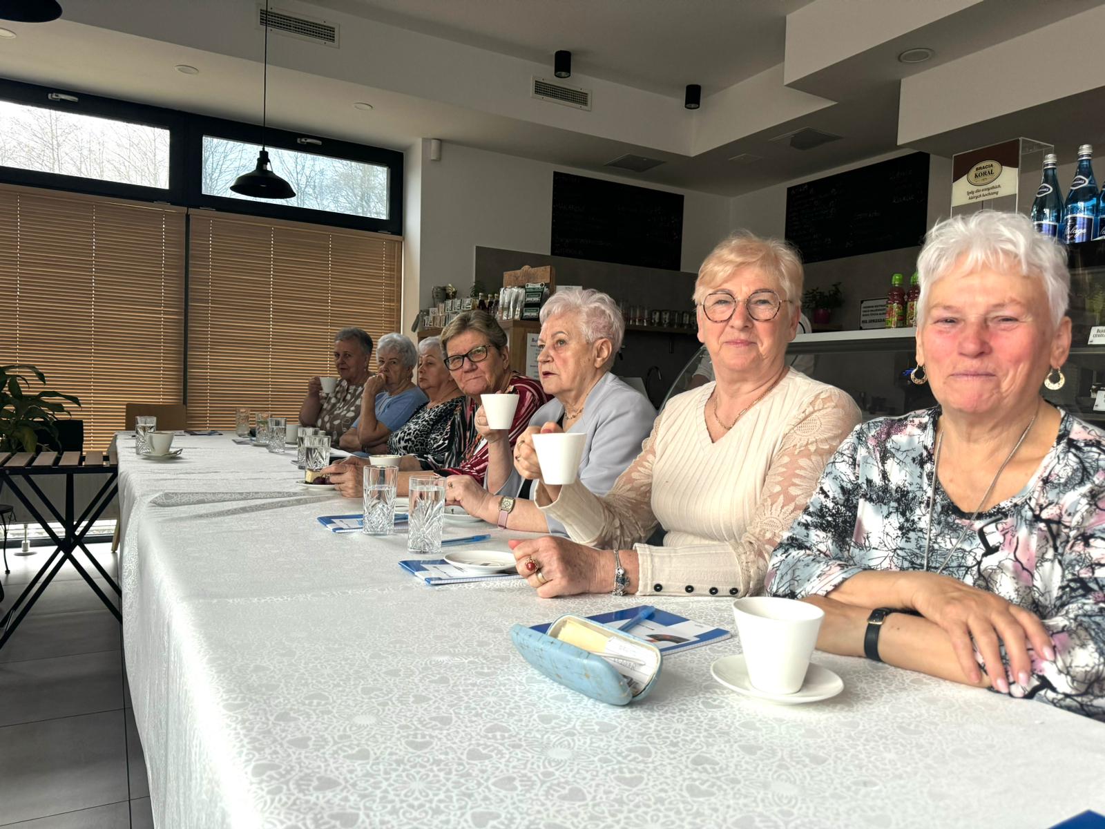 grupa uczestniczek szkolenia siedzi przy stołach